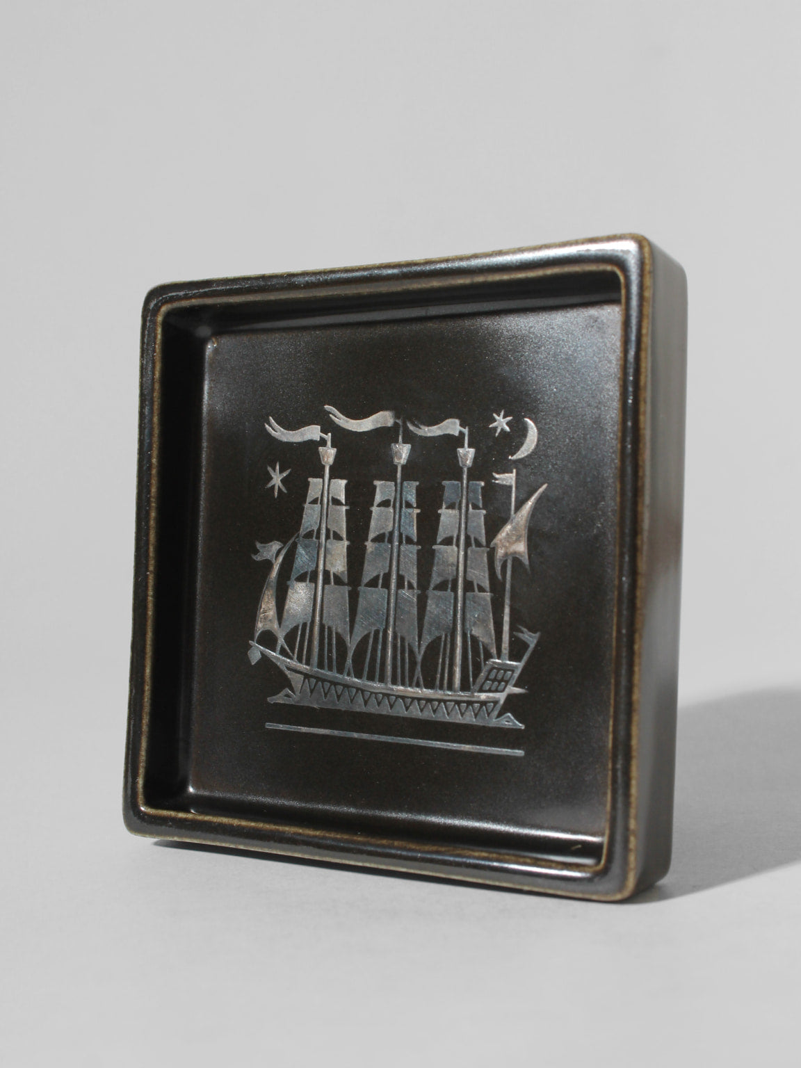 Sven Jonson "Facett" Ceramic Ashtray, For Gustavsberg, 1960s — angled view showing ship design on dark ceramic