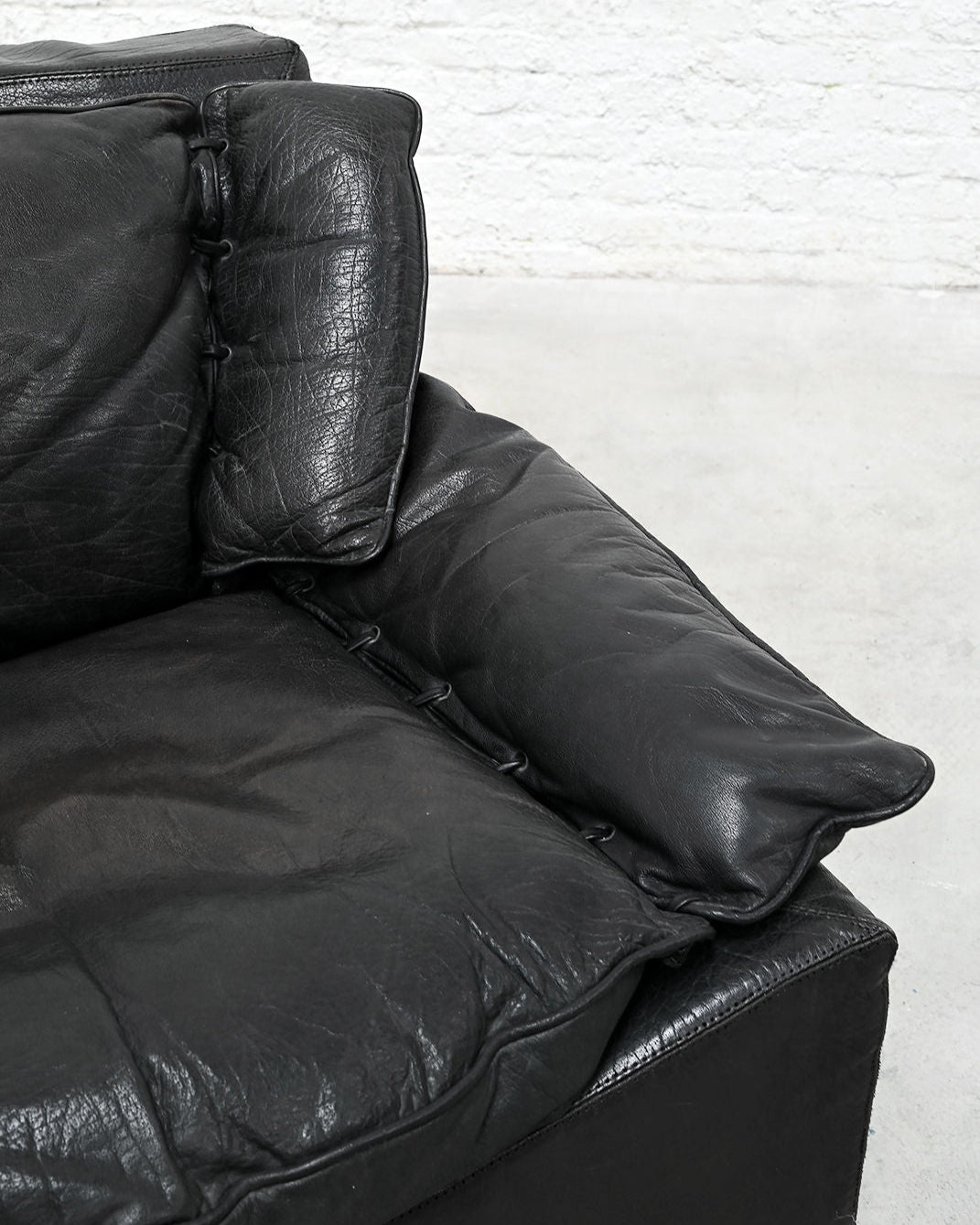 Black leather armchair detail showing button-tufted cushions