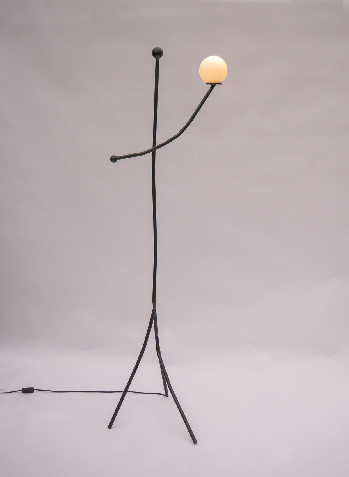 Modern black metal floor lamp with glowing spherical shade and tripod base
