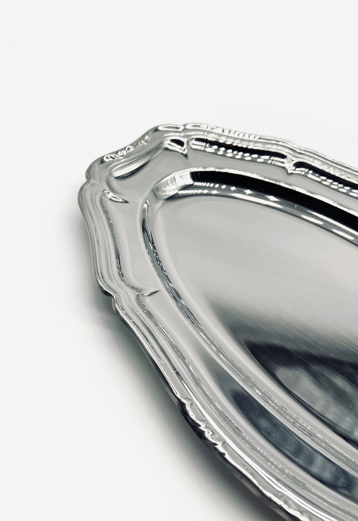 Corner detail of vintage stainless steel serving dish with ornate border