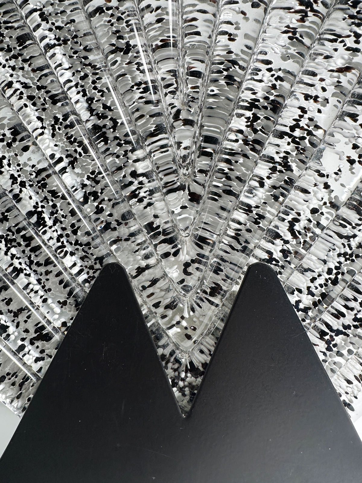 Close-up of the Large Murano glass fan lamp by Dodo Vintage, featuring clear sheets with black speckles, arranged fan-like on a black V-shaped stand—evoking 1980s Art Deco style.