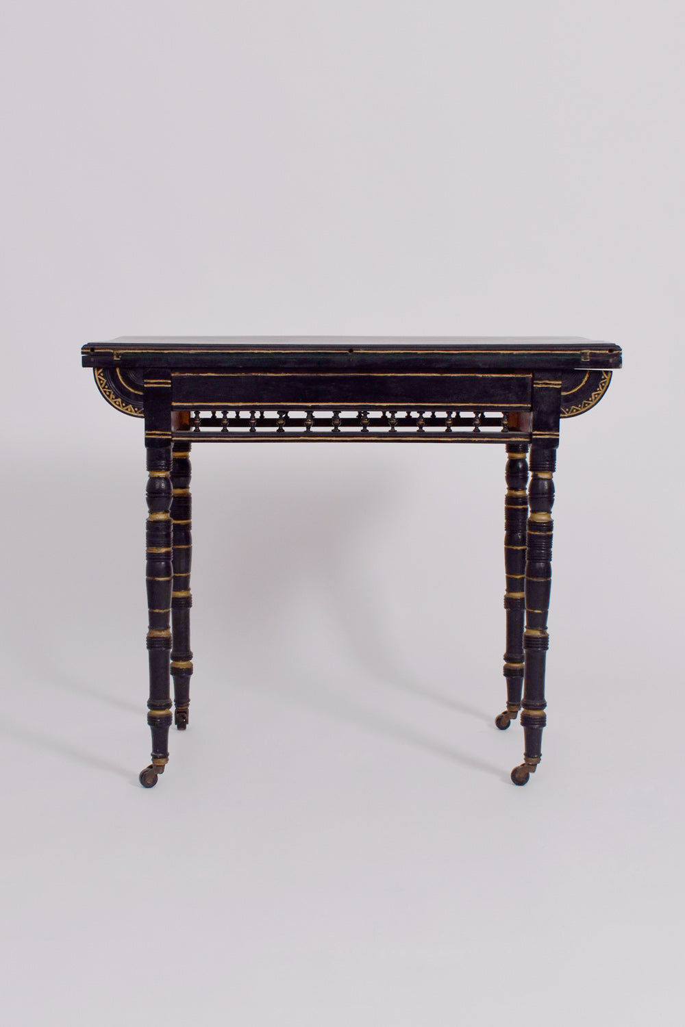 The Godwin Style Ebonised Table by Barracuda Interiors, 19th c., features spindle legs, gold accents, and small casters on each leg, shown against a plain light background.
