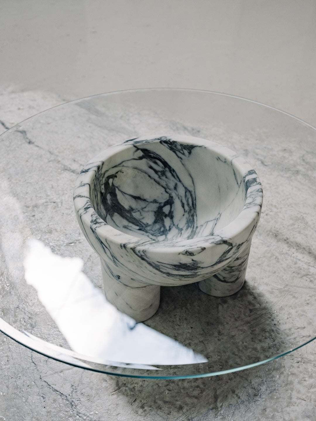 Arabescato marble end table on glass surface showing veined pattern detail