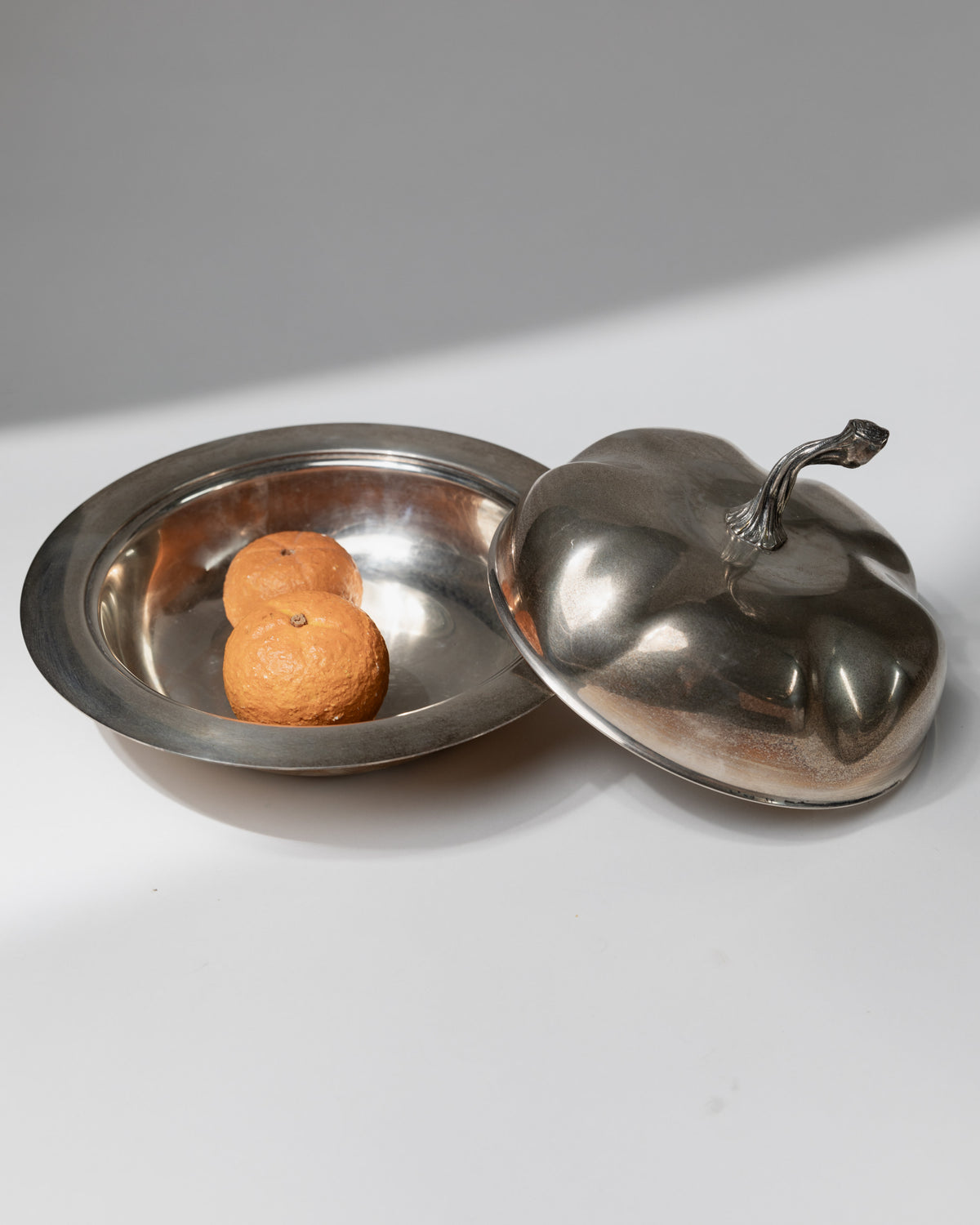 Silver plated serving bowl with ornate lid containing oranges