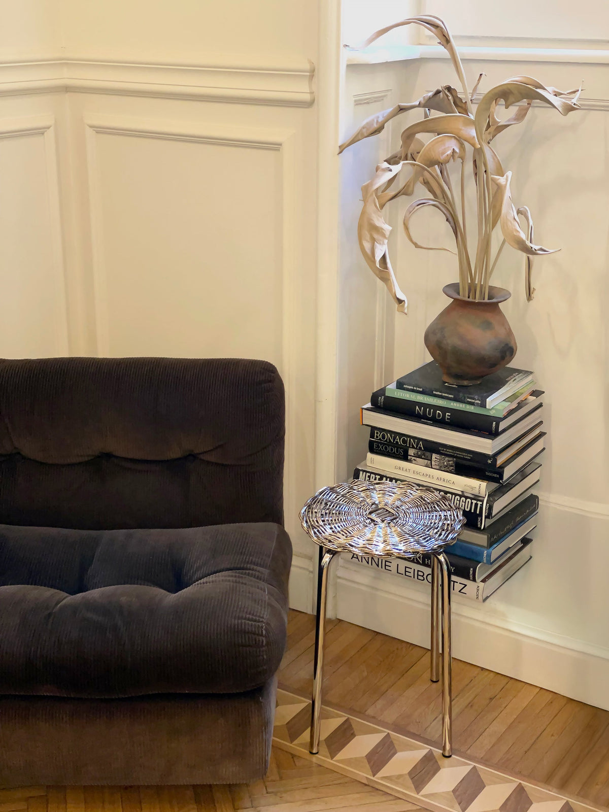 Woven Wicker Metal Plated Side Table in Chrome and Steel — angled view beside a dark sofa