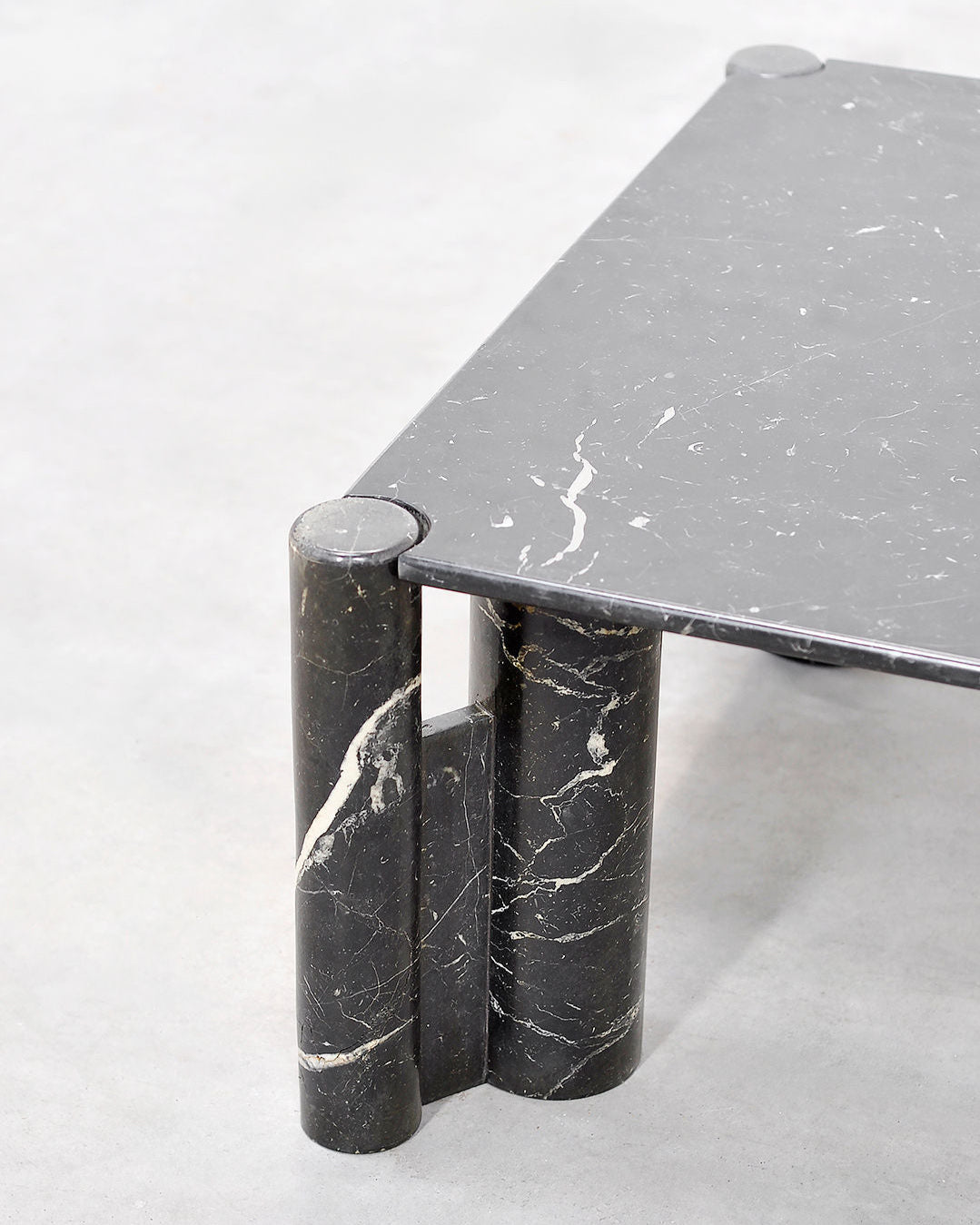 Detail view of cylindrical marble base supporting grey marble coffee table top