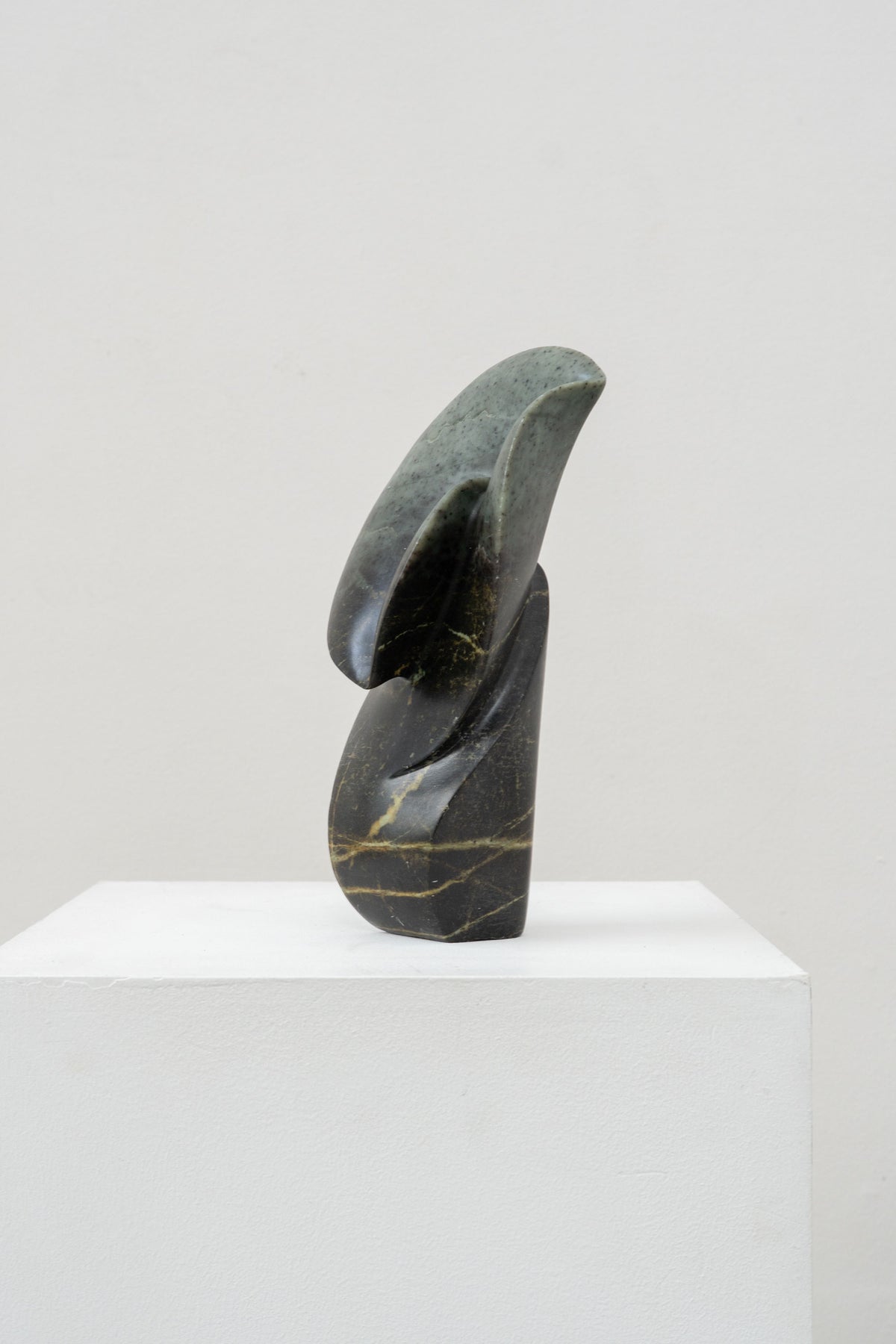 Abstract curved stone sculpture with dark marble and green veining