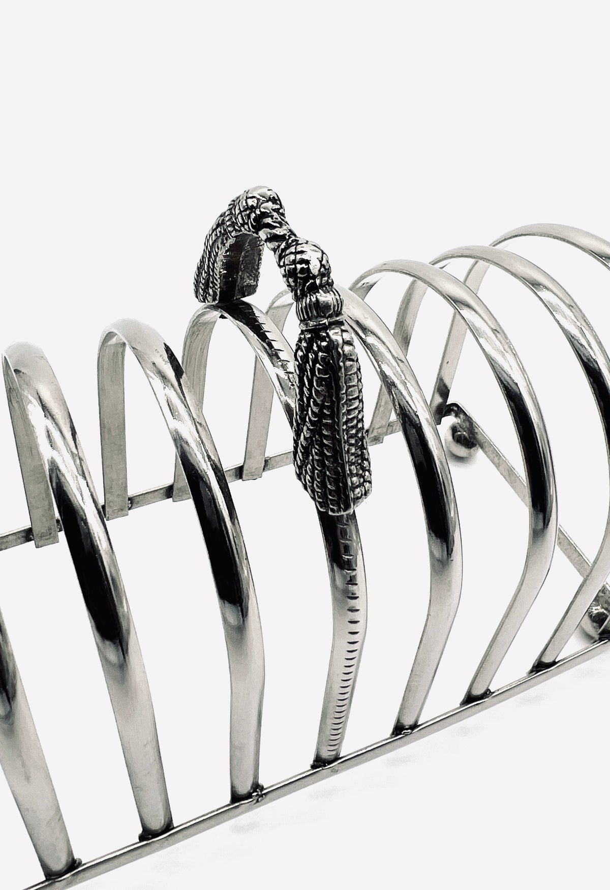 Silver-plated toast rack with ornate tassel handle detail view
