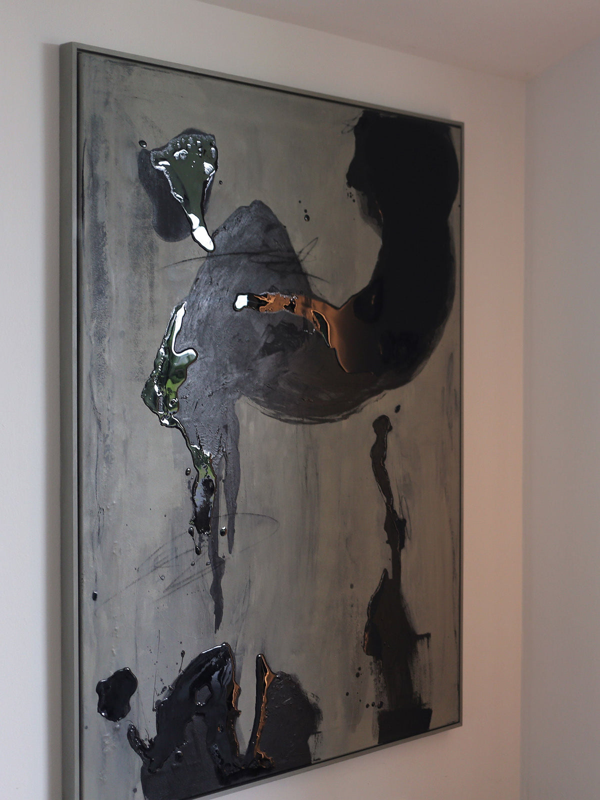 Black Drift - Painting by STUDIOPOLS features black, dark gray, green, and white acrylic smudges on a light gray background. The framed artwork is displayed on a white wall in a well-lit room.