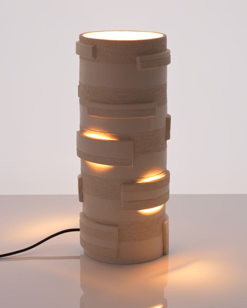 The "Bricks" Table Lamp by Katia Langeard features a modern ceramic design with geometric cut-out patterns, casting warm, glowing shapes—ideal as an accent light for hallways or glossy surfaces.