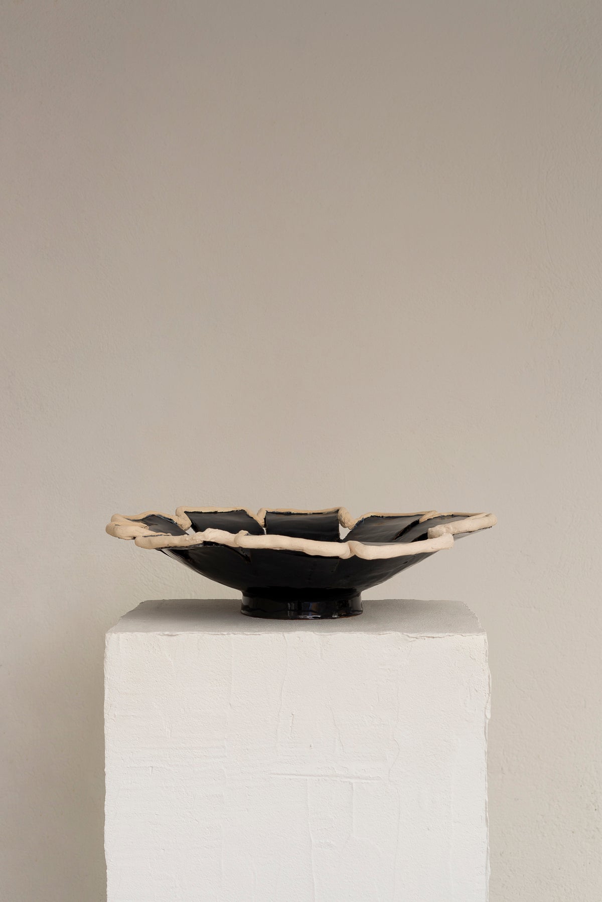 Navy blue ceramic decorative dish with raw clay rim detail, profile view