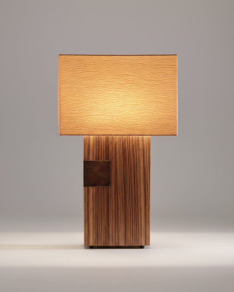 Pollux table lamp with textured shade on wood-paneled desk