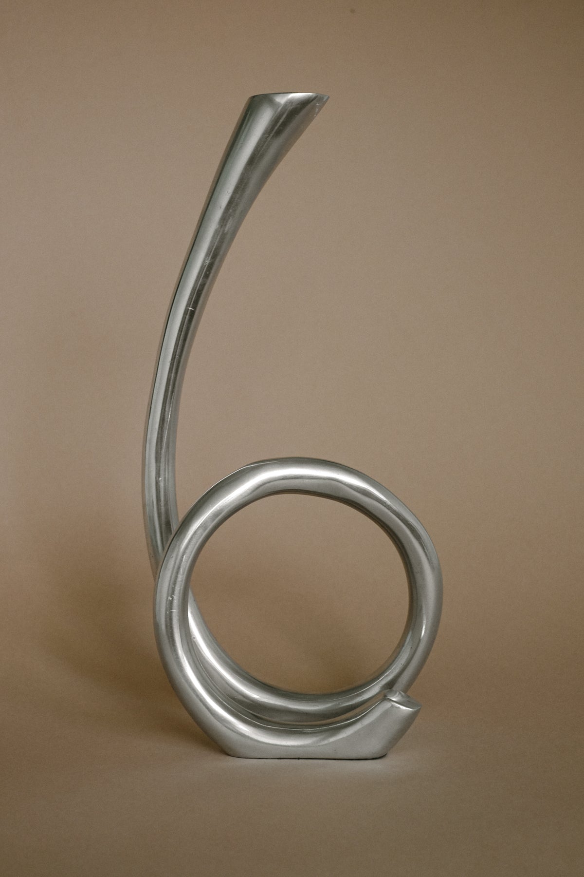 Sculptural metal candleholder with curved loop design detail