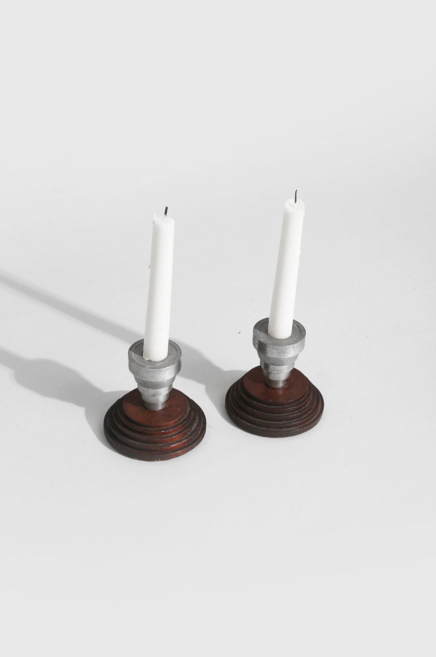 Two ceramic stair step candleholders with white candles, walnut base