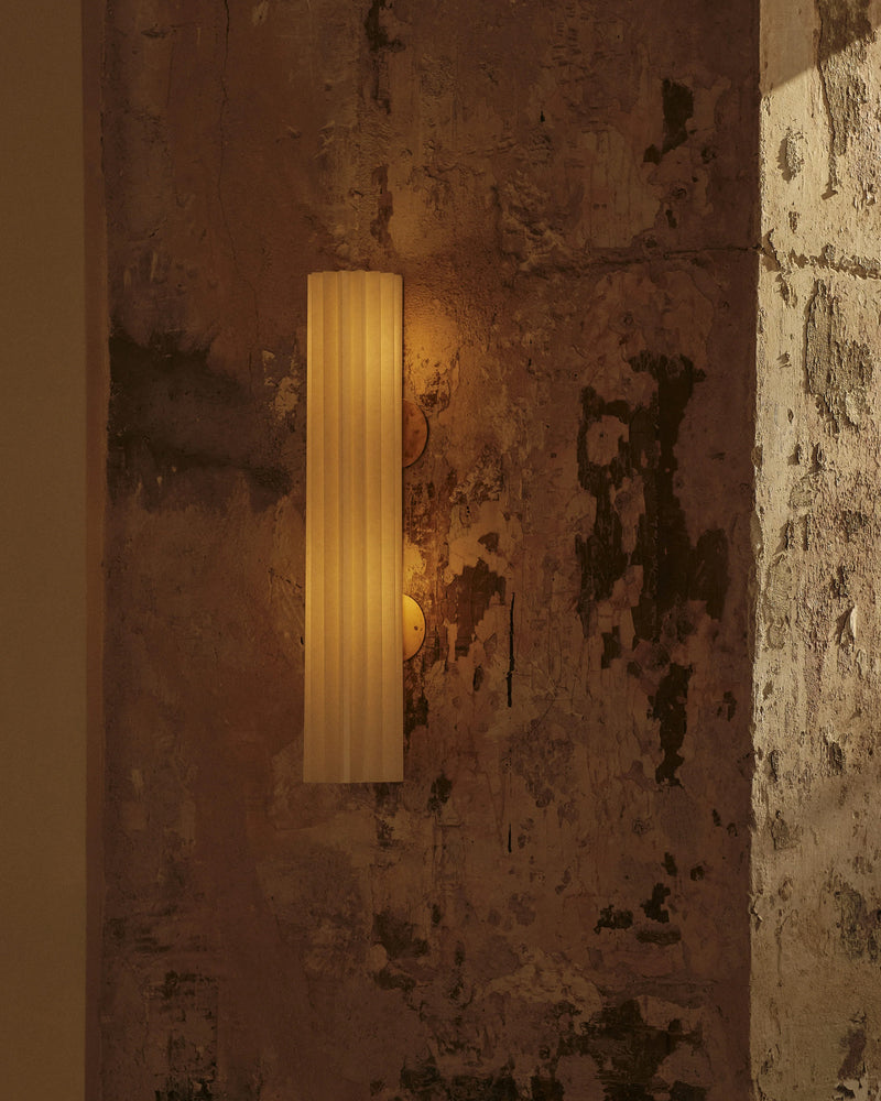 Uma Arandela 2 cylindrical wall light with warm glow on aged wall