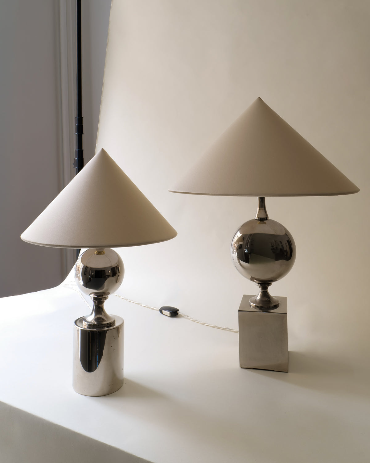 Two Barbier chrome table lamps with conical cream shades on white surface