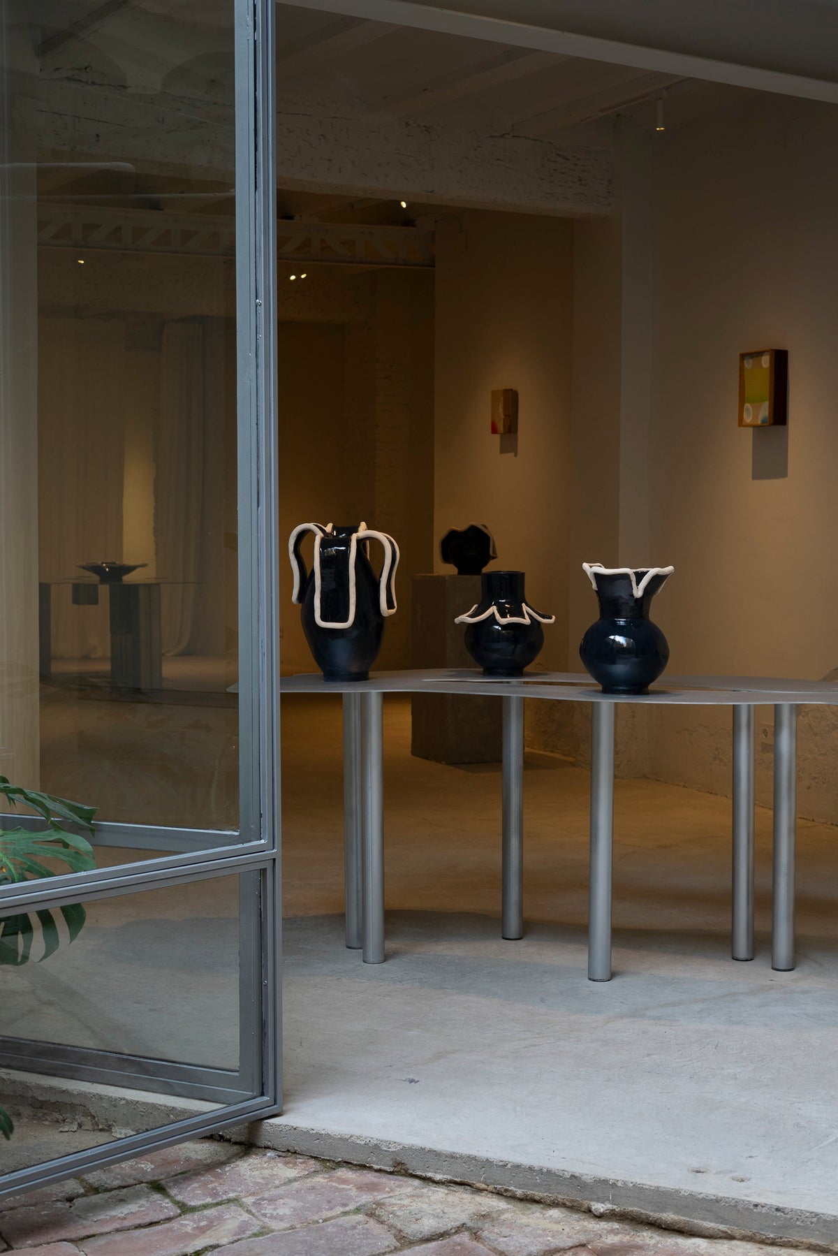 Navy blue ceramic vases with white clay handles, gallery display