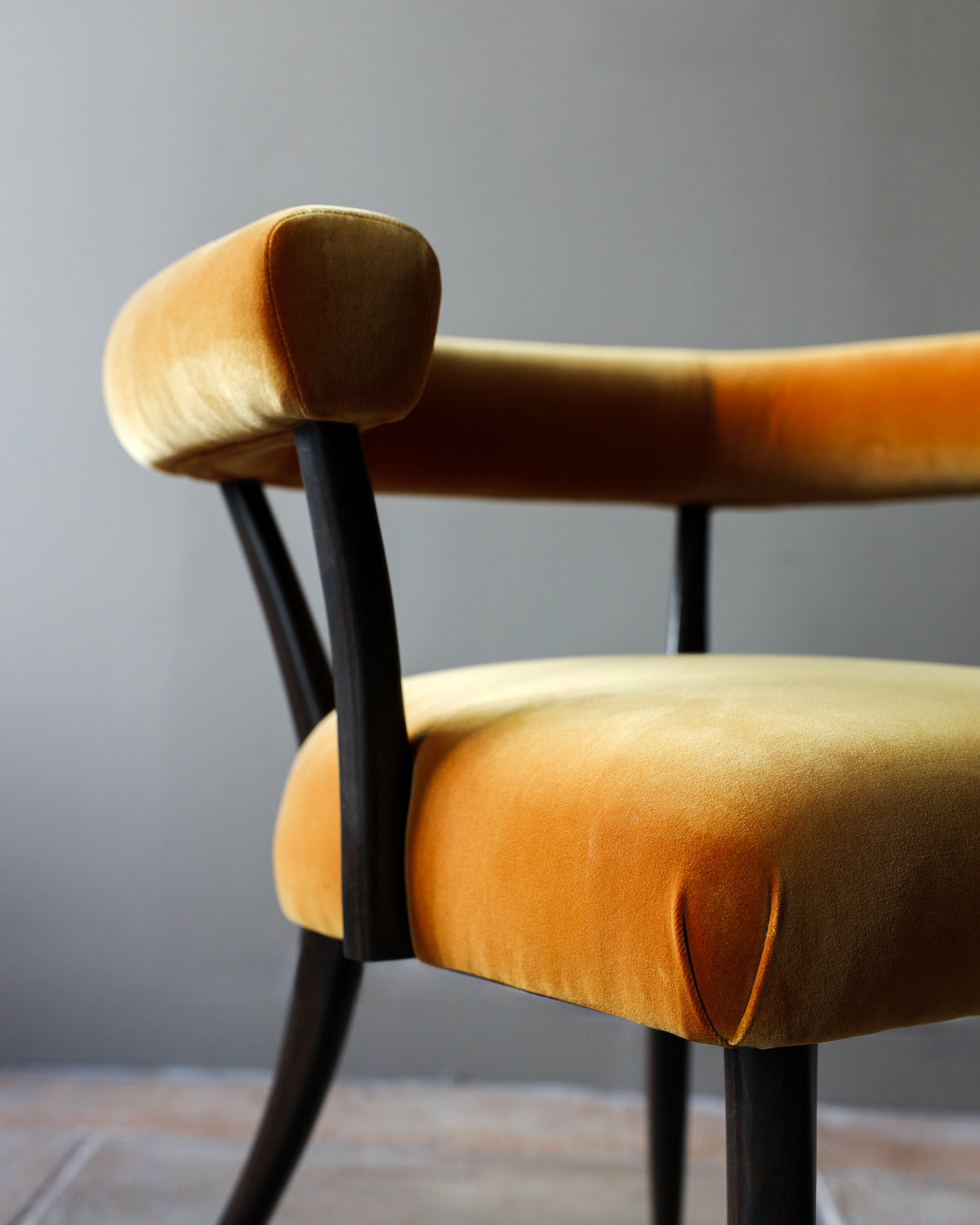 Josef dining chair detail view showing curved orange velvet upholstery and black wood frame