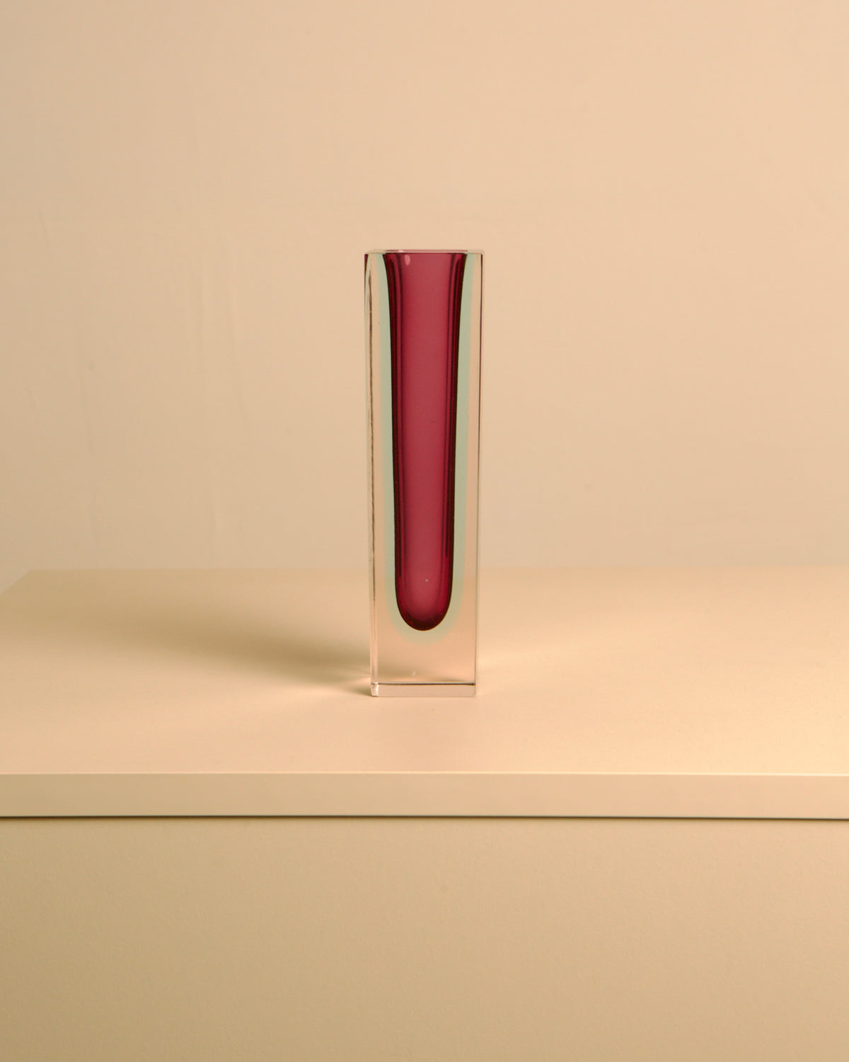Tall red Murano glass vase in clear block, side view angle