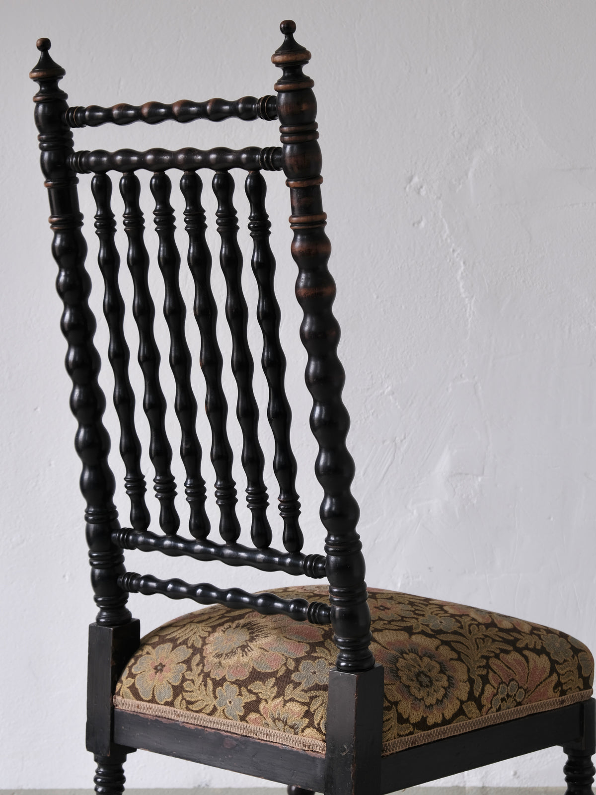 Dark oak bobbin chair back detail with upholstered floral seat