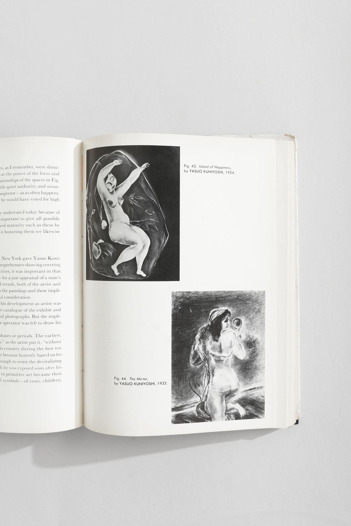 Open art book showing Yasuo Kuniyoshi nude figure paintings from 1920s