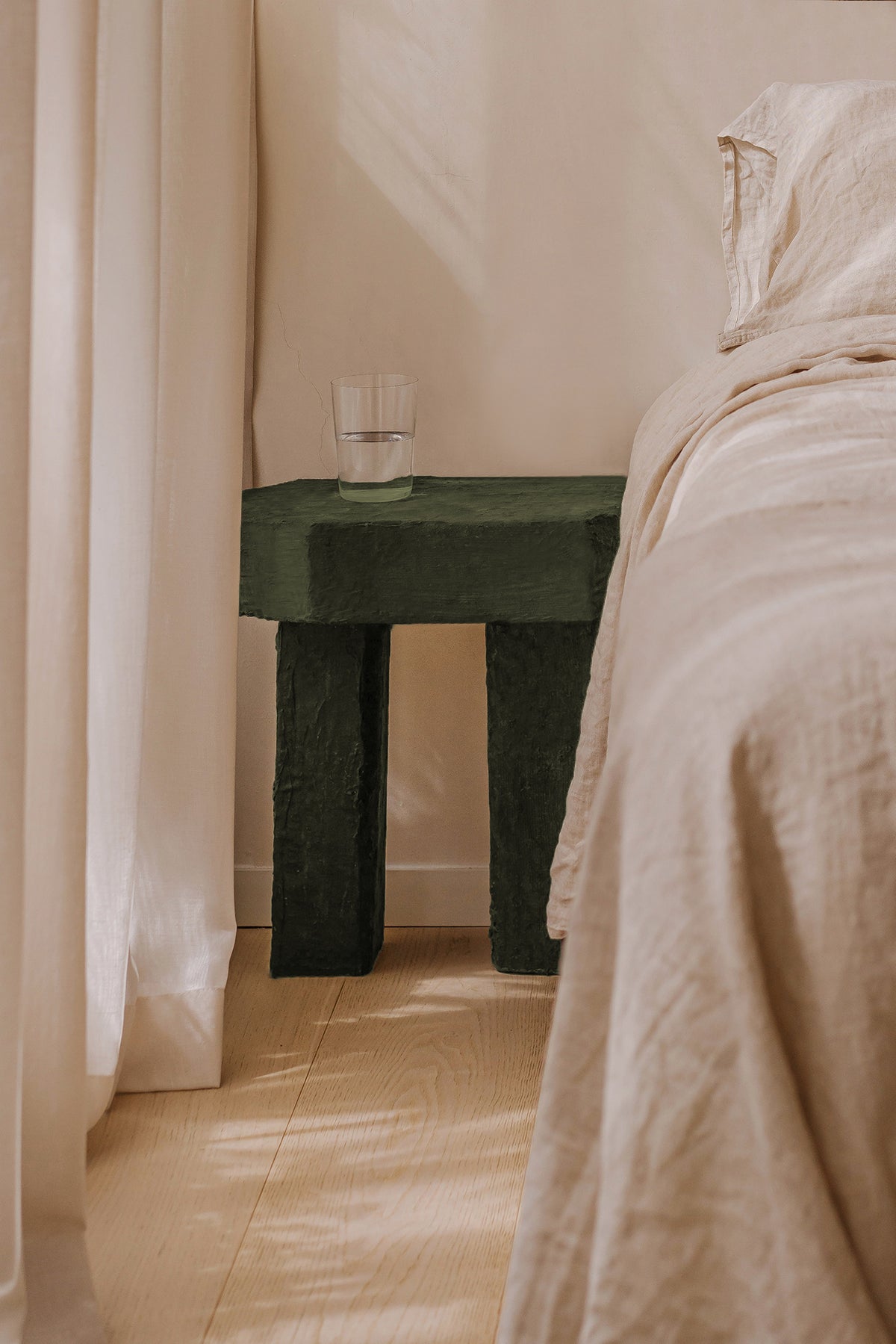 Green stone Ruins side table by Szymon Keller in bedroom setting