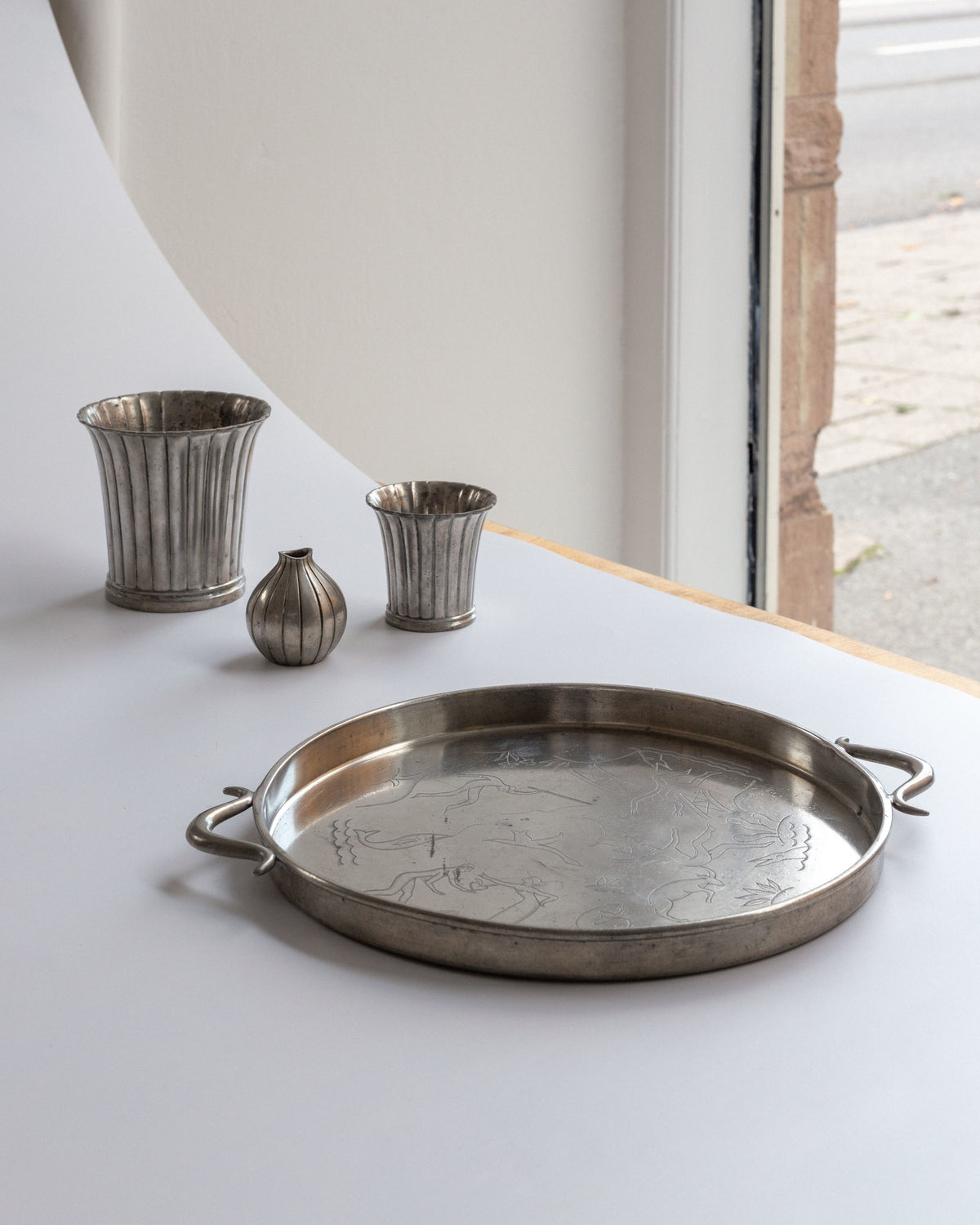Art Deco pewter tray with matching vases styled on white surface