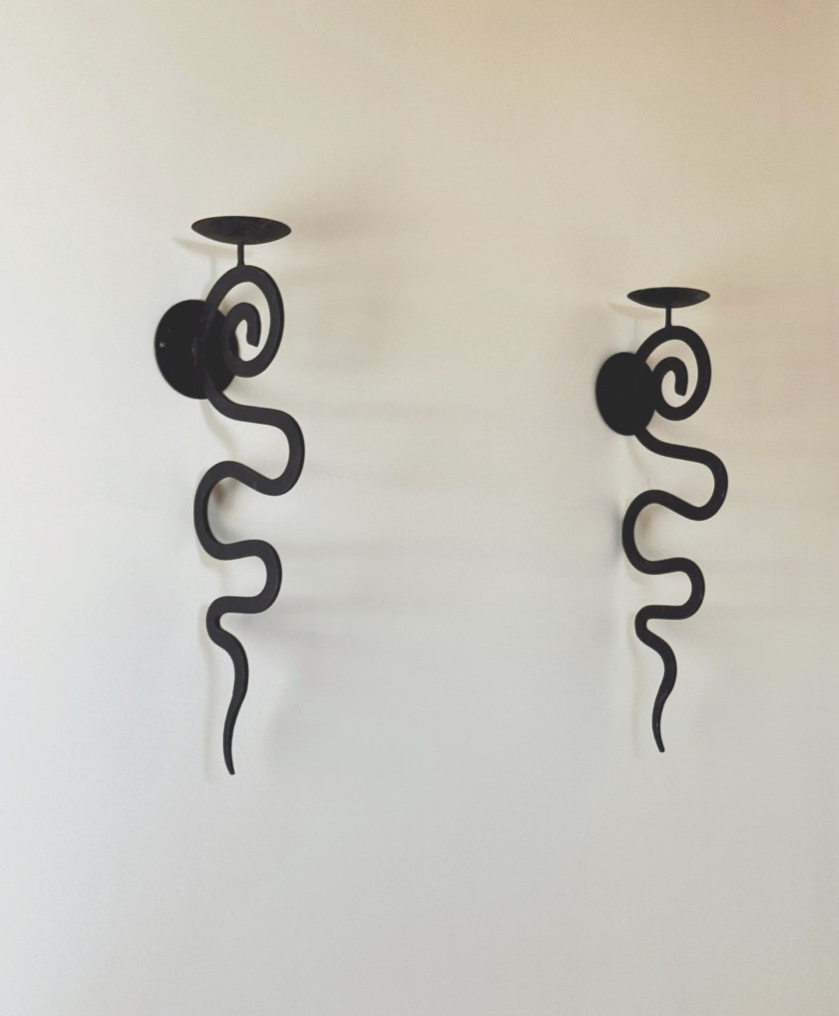Black wrought iron serpentine wall sconces with candle holders