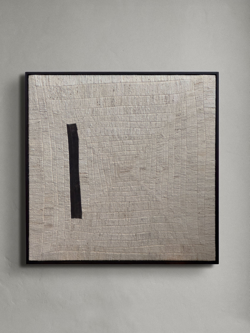 The "to tilt, 2024" artwork by Bec Kirby features a textured square design with concentric, unevenly carved lines creating a spiral pattern. A vertical black stripe, thicker in the center, disrupts the pattern on the left. This piece is elegantly framed in solid oak and displayed against a neutral wall.