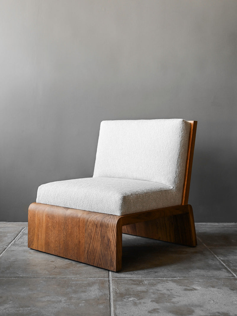 Modern lounge chair with light gray upholstery and curved wood base