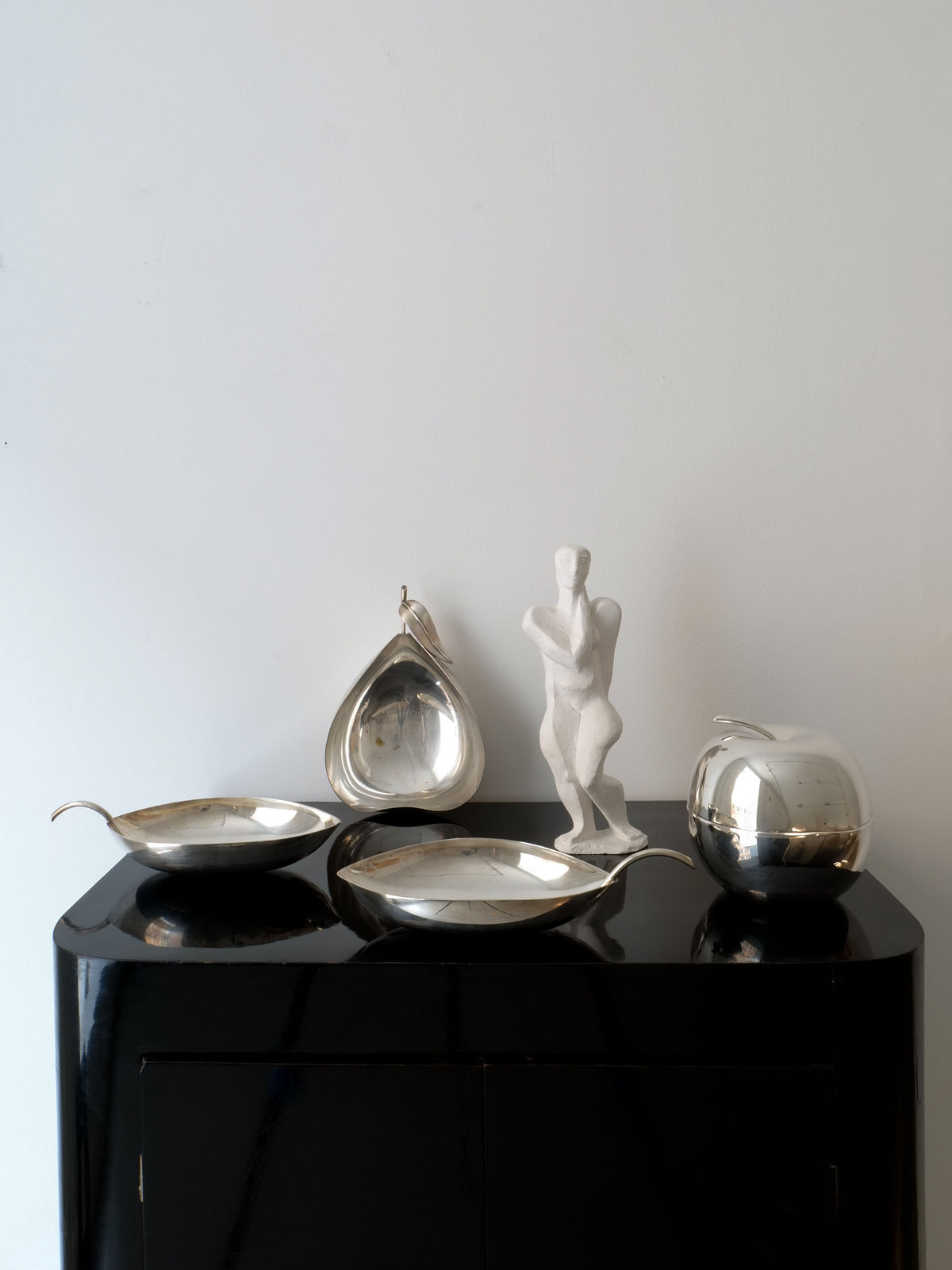 A sleek black table against a plain white wall is elegantly adorned with the Christofle Vide Poche Lino Sabattini from Collection apart.