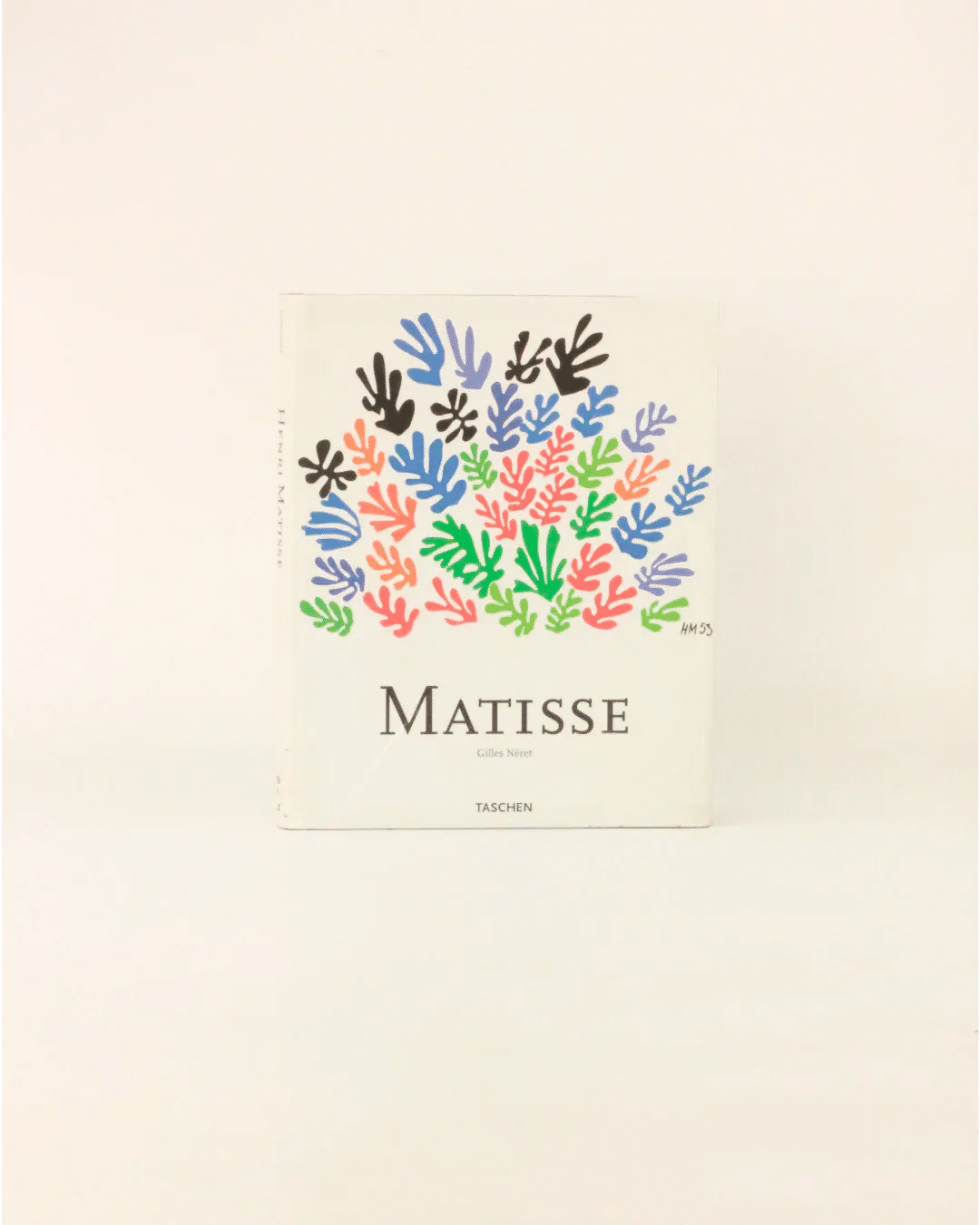 A book titled "Henri Matisse Vintage Book - Illustrated Publication" by Boga Avante Shop stands upright against a plain background. The cover showcases colorful abstract shapes resembling leaves or coral in blue, pink, green, red, and black, inspired by Henri Matisse's iconic gouache cut-outs in modern art.