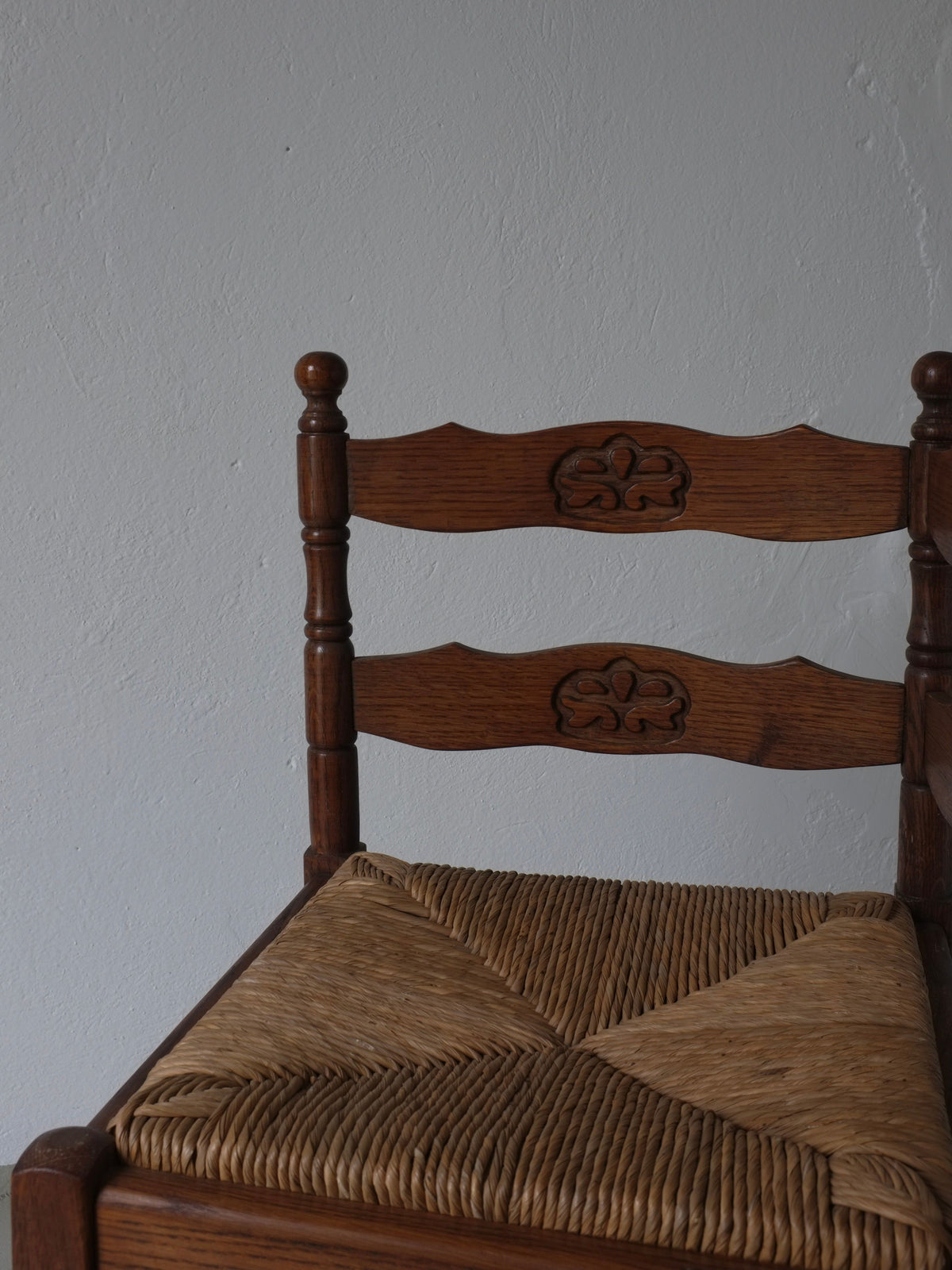 Corner detail of carved oak chair showing woven rush seat