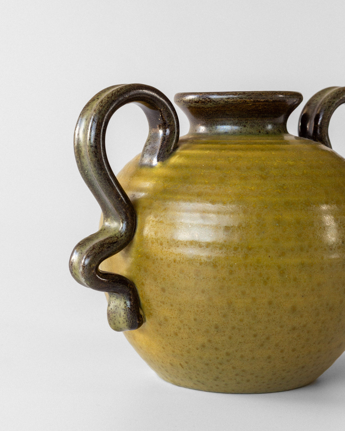 Curved serpentine handles detail of vintage Oliv ceramic vase