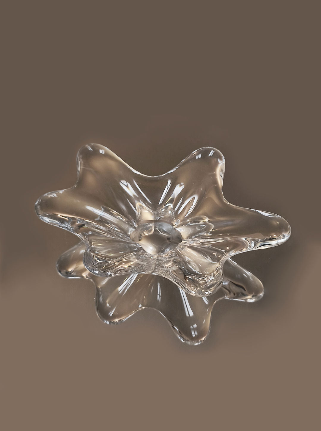 The Les Objoies Crystal Baccarat Cup, with its wavy, translucent petals, showcases refined crystal artistry. It sits elegantly on a neutral light brown background, its glossy finish reflecting light and accentuating its graceful curves.