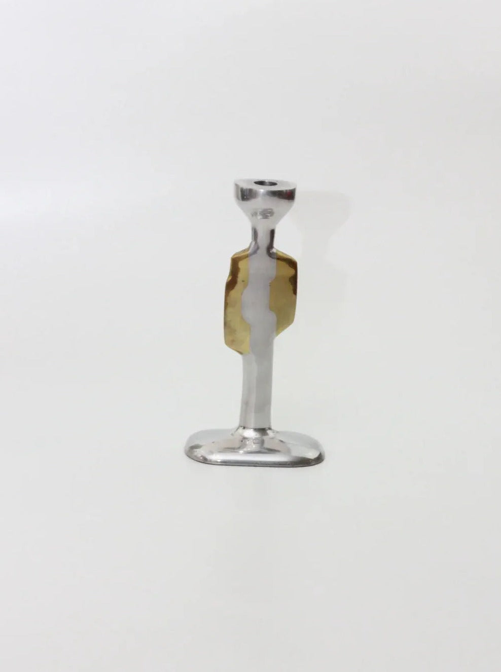 Introducing the Pair of Brutalist Candleholders from Boga Avante Shop. These candleholders feature a polished silver base and a thin, elongated stem adorned with a golden decorative element at the center, reminiscent of David Marshall-Diseños' iconic style. Merging luxury with minimalism, they are showcased against a plain white background, bringing an elegant touch to any space.
