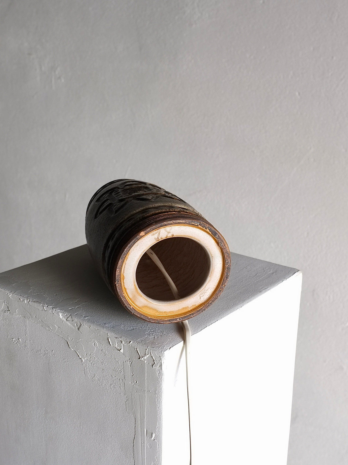 Cylindrical stoneware lamp detail showing ridged texture and cord