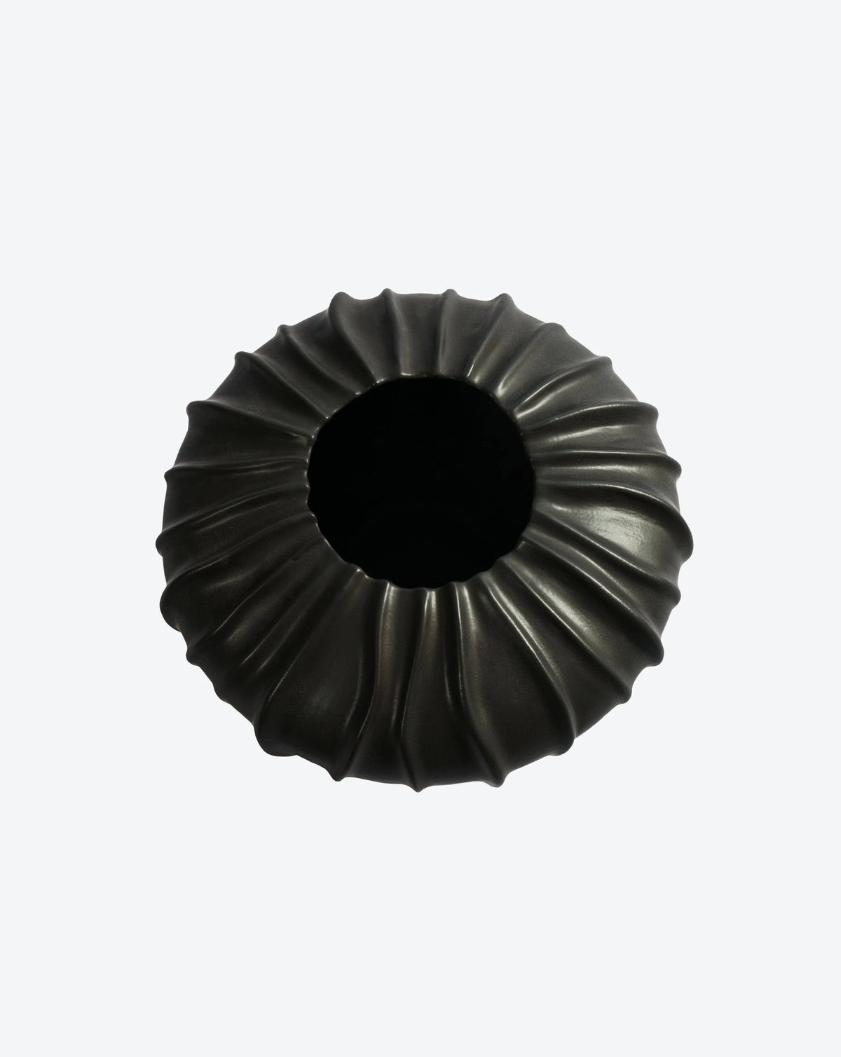 A top-view of the Ransom & Dunn Wide Cloak Vase, a piece from their handcrafted Cloak ceramic collection made in Portugal, shows a black, circular object featuring a ruffled, petal-like pattern encircling a central round opening set against a plain white backdrop.