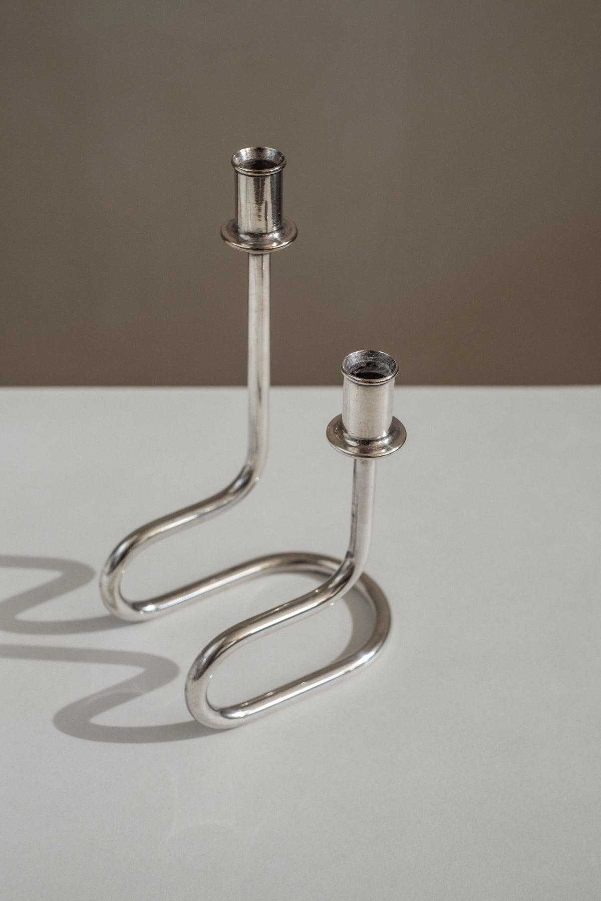 Modern curved silver candleholders showing sculptural S-shaped design