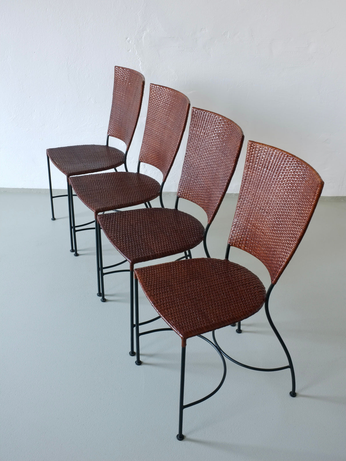 Four vintage wrought iron wicker chairs arranged in perspective