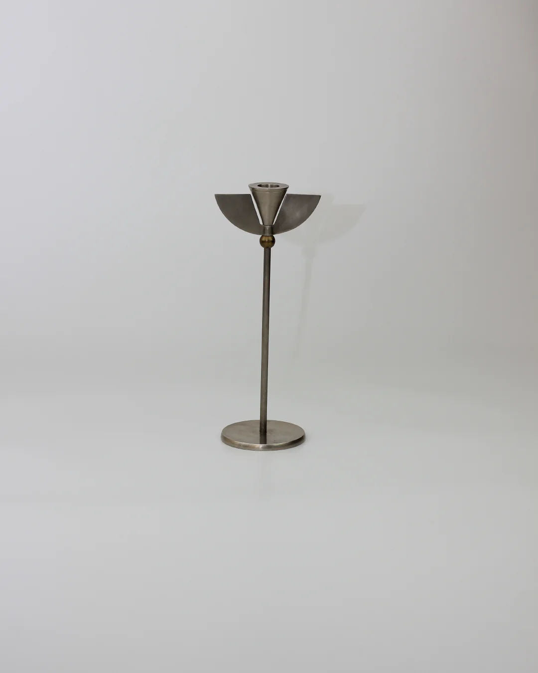 The Memphis Candleholders 80s by Boga Avante Shop, inspired by Memphis Milano design, showcase a minimalist silver metal build with a round base and angular geometric holder, perfectly centered on a plain white background.
