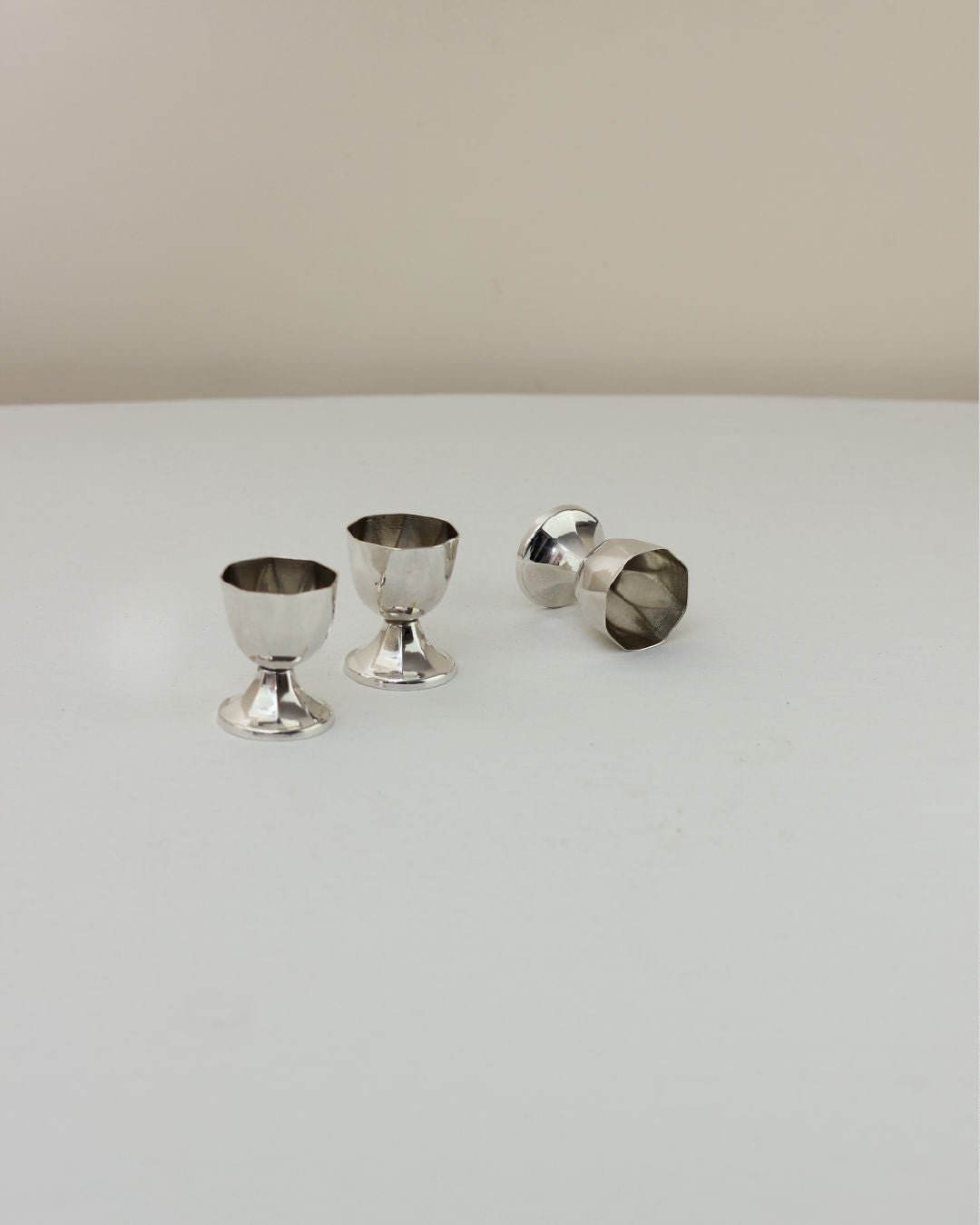 Three silver vintage egg cups, two upright and one tipped over