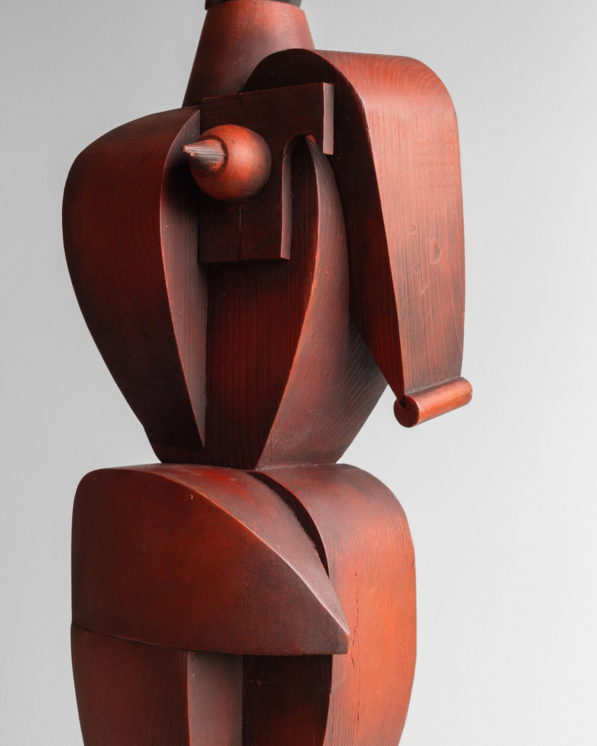 The Vintage Cubist Sculpture II by Atelier Boulogne from Spigel is a wooden piece with geometric shapes, curved elements, and sharp angles. It features a smooth reddish-brown finish against a plain gray background, resembling a stylized female figure.