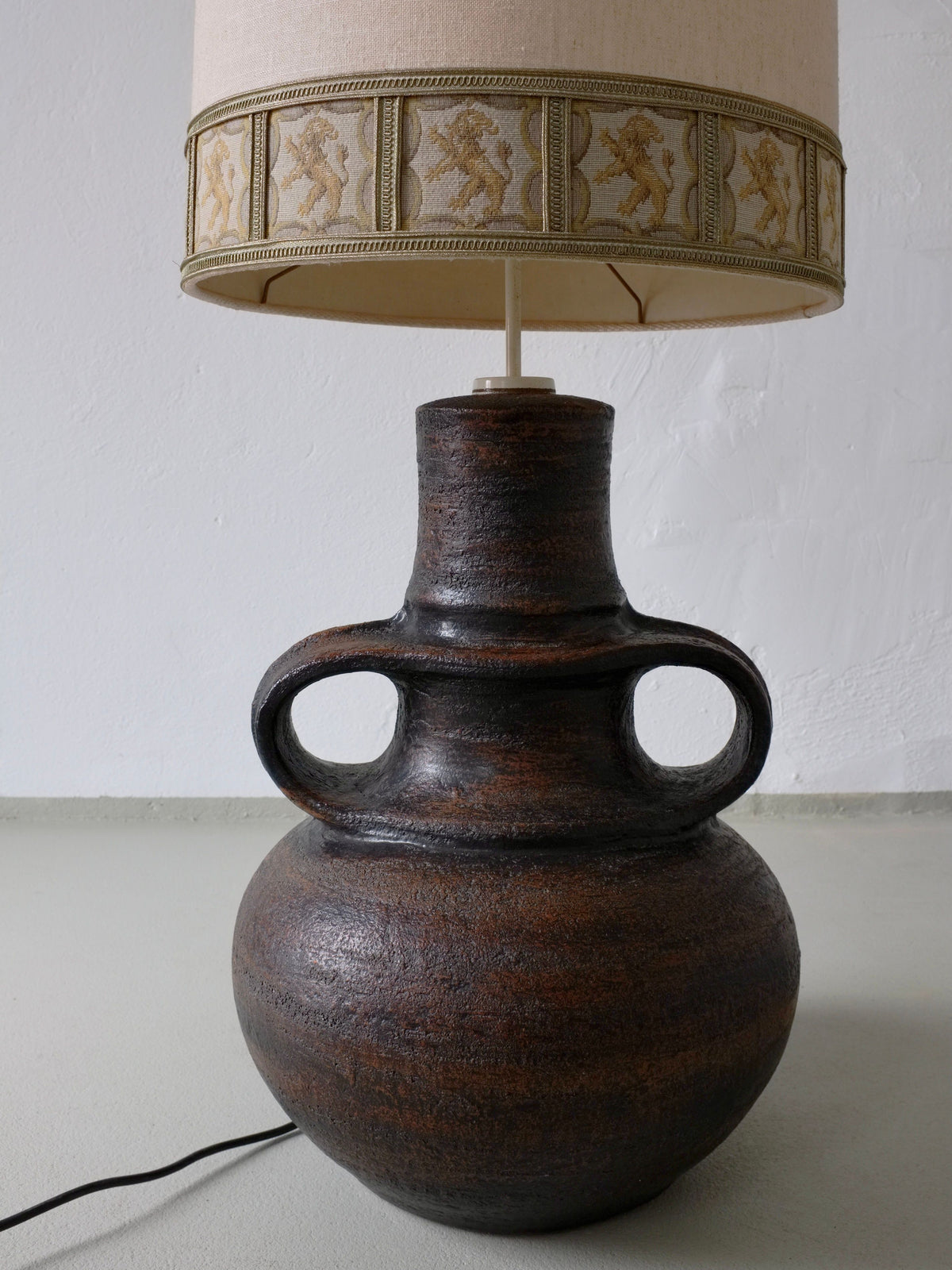 Brutalist ceramic lamp with ornate shade featuring heraldic lions