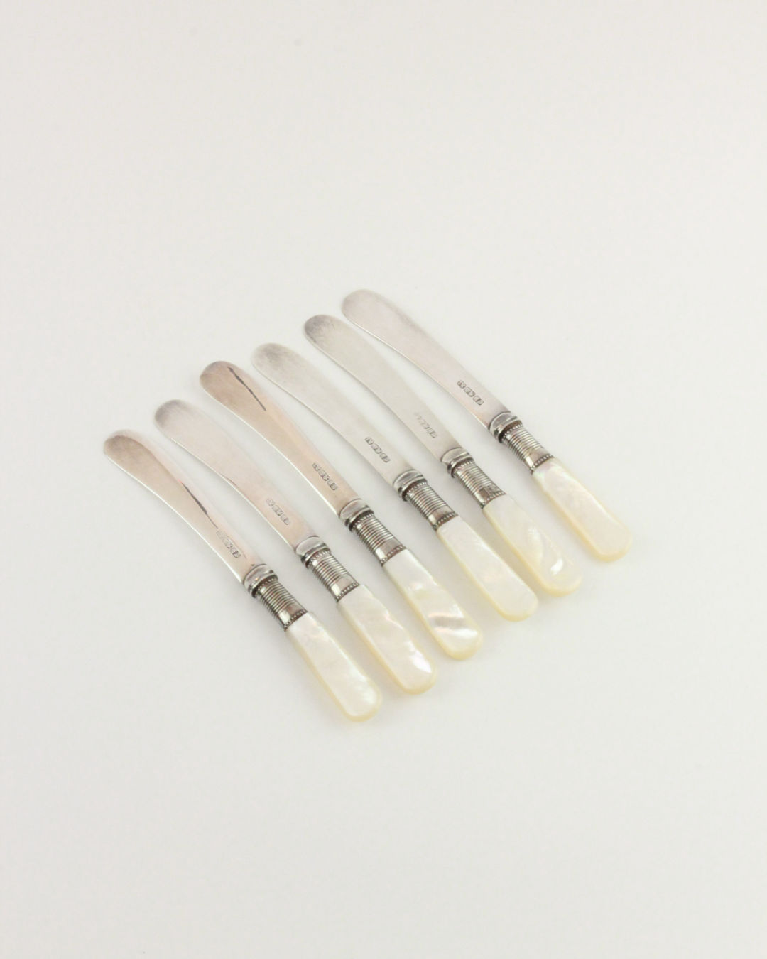 Six Boga Avante Shop Mother-of-pearl Butter Knives, each with a silver-toned blade and elegant mother-of-pearl handle, are neatly arranged in a row on a plain white background.