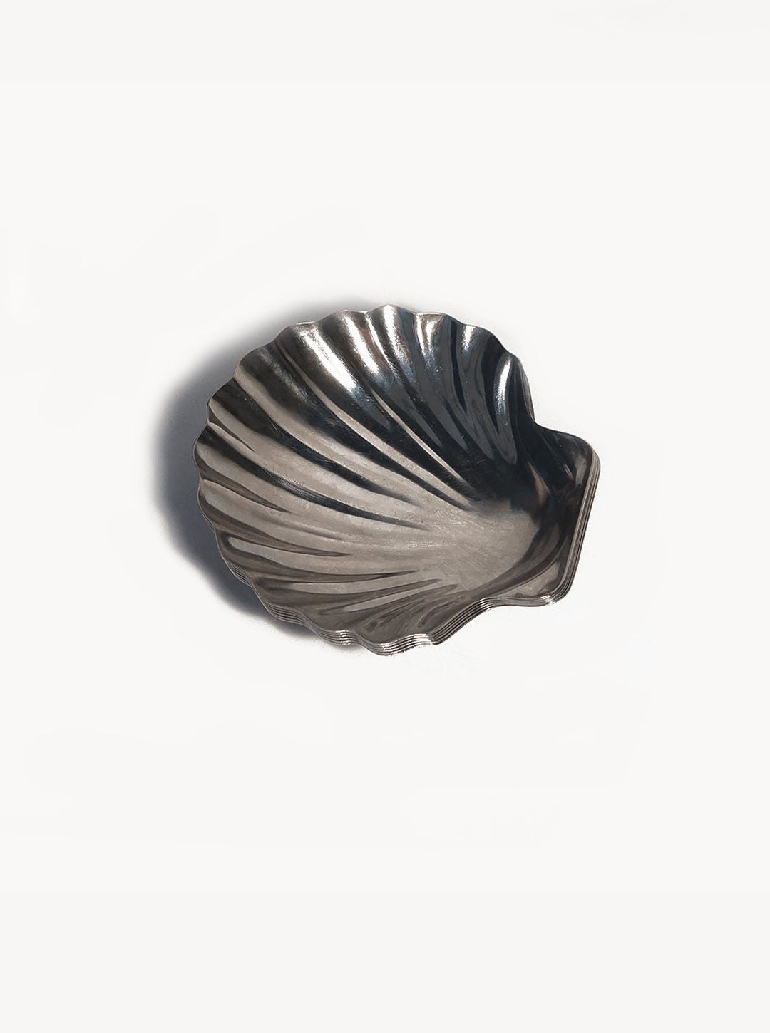 A set of 6 small shell dishes by Les Objoies in stainless steel with a glossy finish, featuring detailed grooves that mimic the natural lines of a shell. The set of 6 small shell dishes, placed on a plain white background, highlights their elegant and shiny texture, perfect for elevating any dining experience.