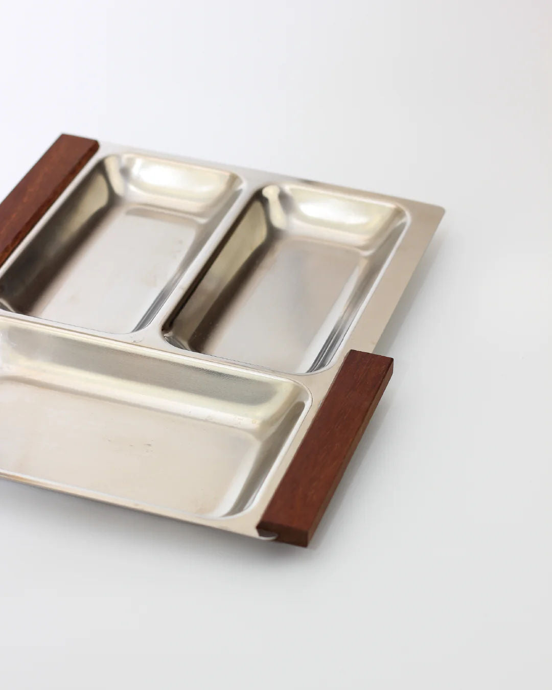 The Boga Avante Shop's Stainless Steel Danish Tray 70s features a sleek, modern design with three metal compartments and elegant teak wood handles, making it perfect for stylish presentations on any light surface.