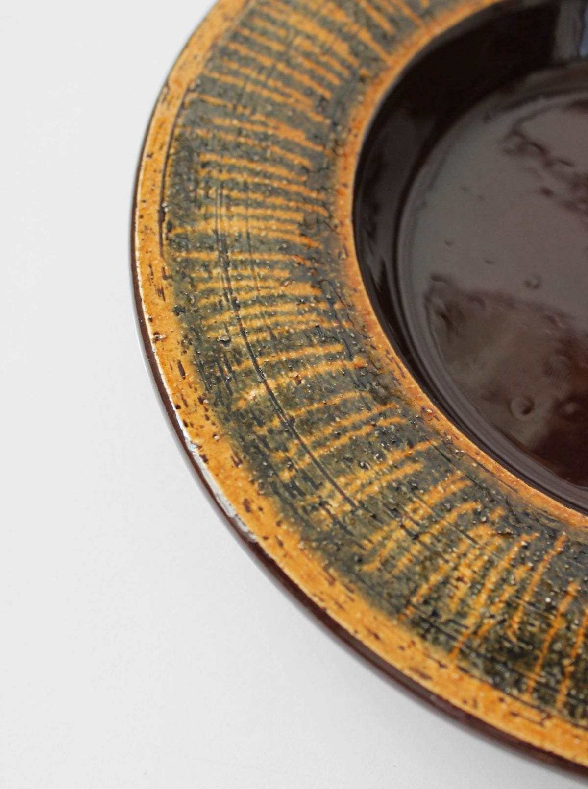 Close-up detail of Gabriel ceramic plate's textured rim with weathered glaze