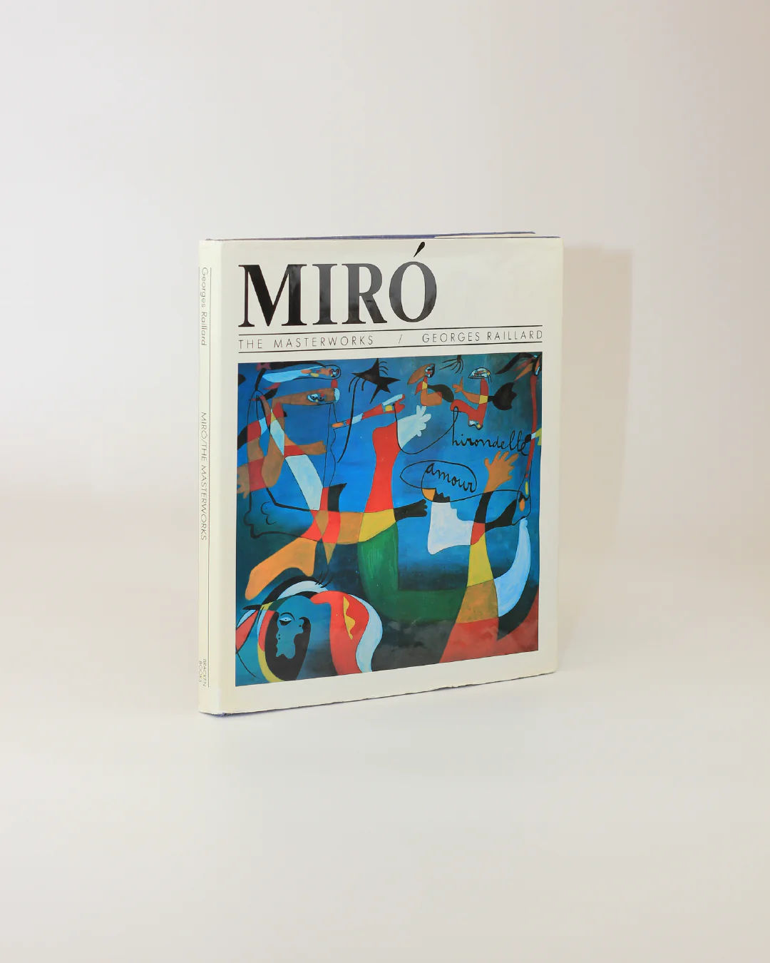 The cover of Boga Avante Shop's "Mirò The Masterworks Book" by Georges Raillard boasts a vibrant abstract painting with blue, red, and yellow shapes and lines. It elegantly stands against a plain light background, celebrating Joan Miró's genius in surrealism.