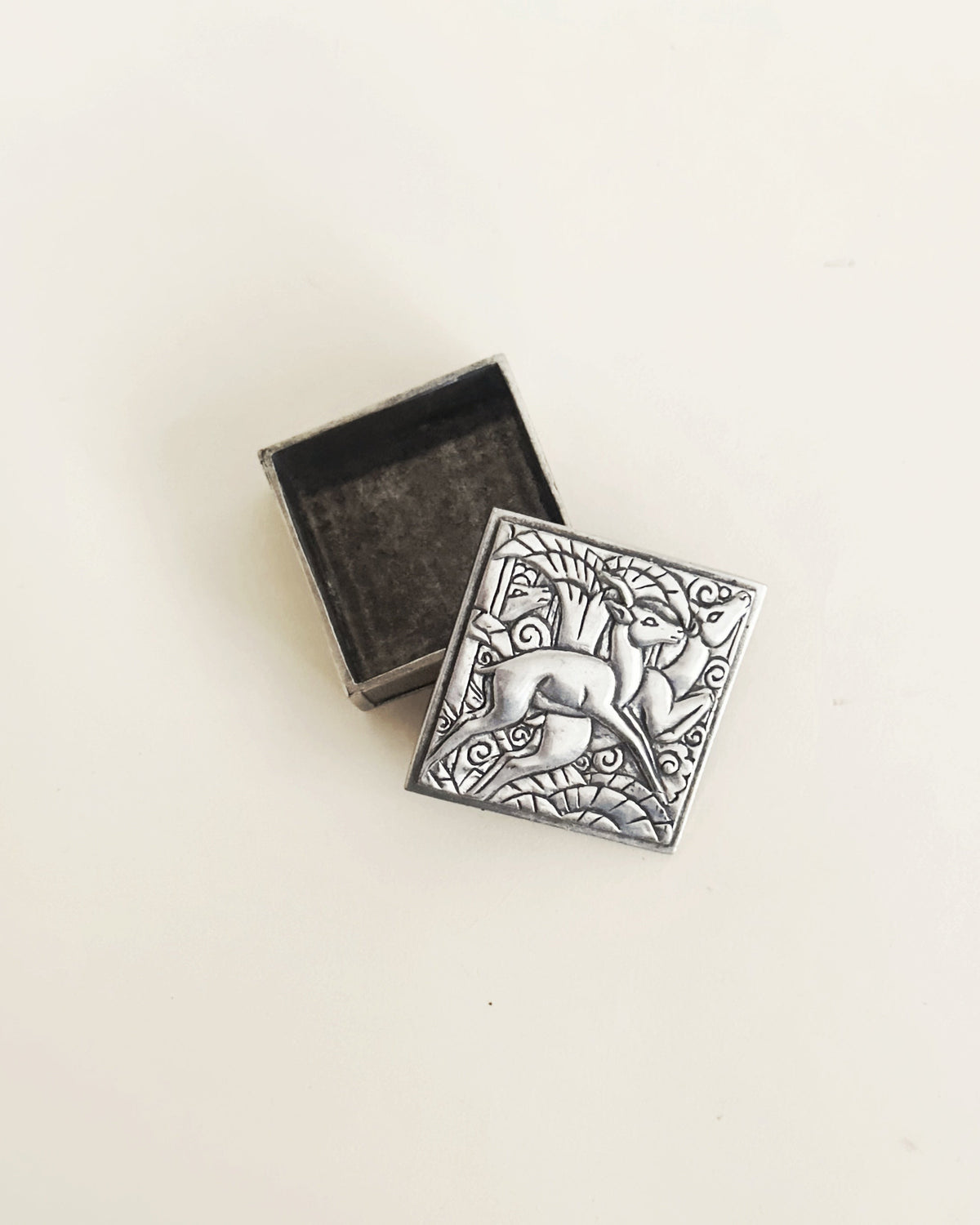 Art Deco pewter trinket box with ornate dolphin relief design